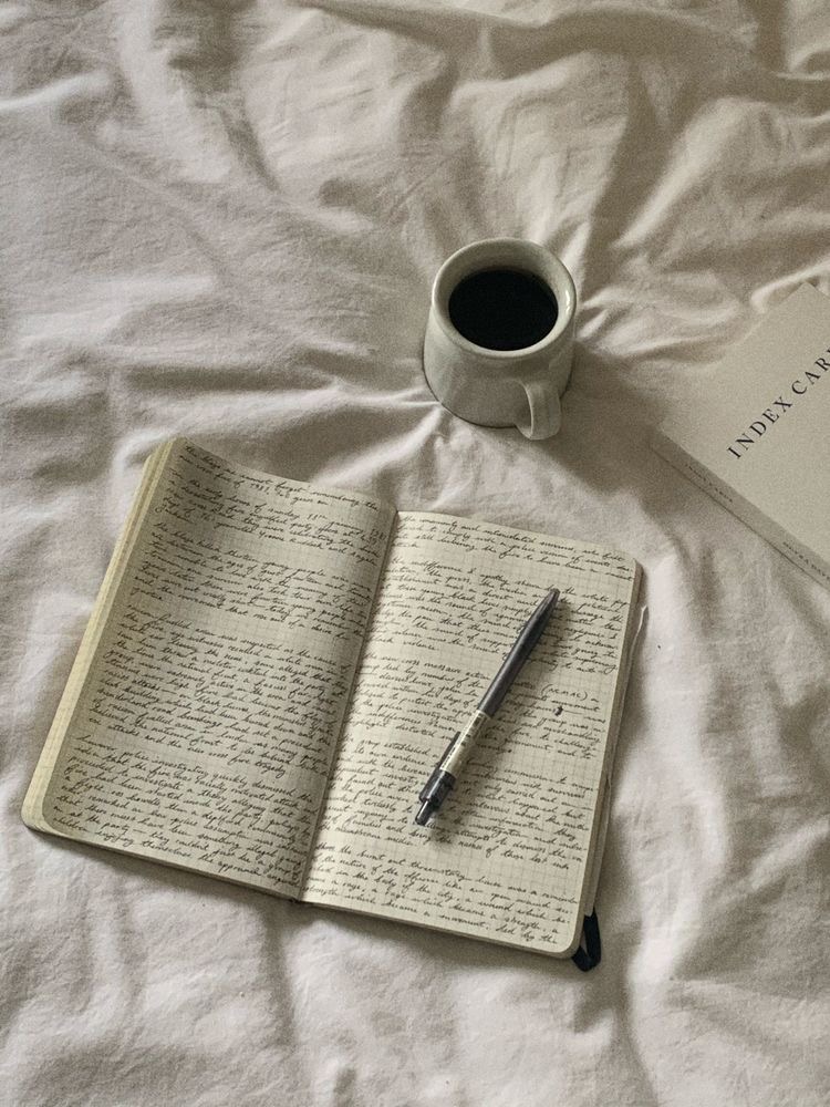 Un cahier avec de l'écriture et un café sur un fond de couverture blanche